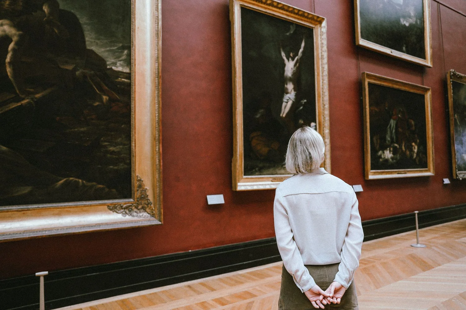 Personne de dos observant des tableaux anciens dans une galerie de musée