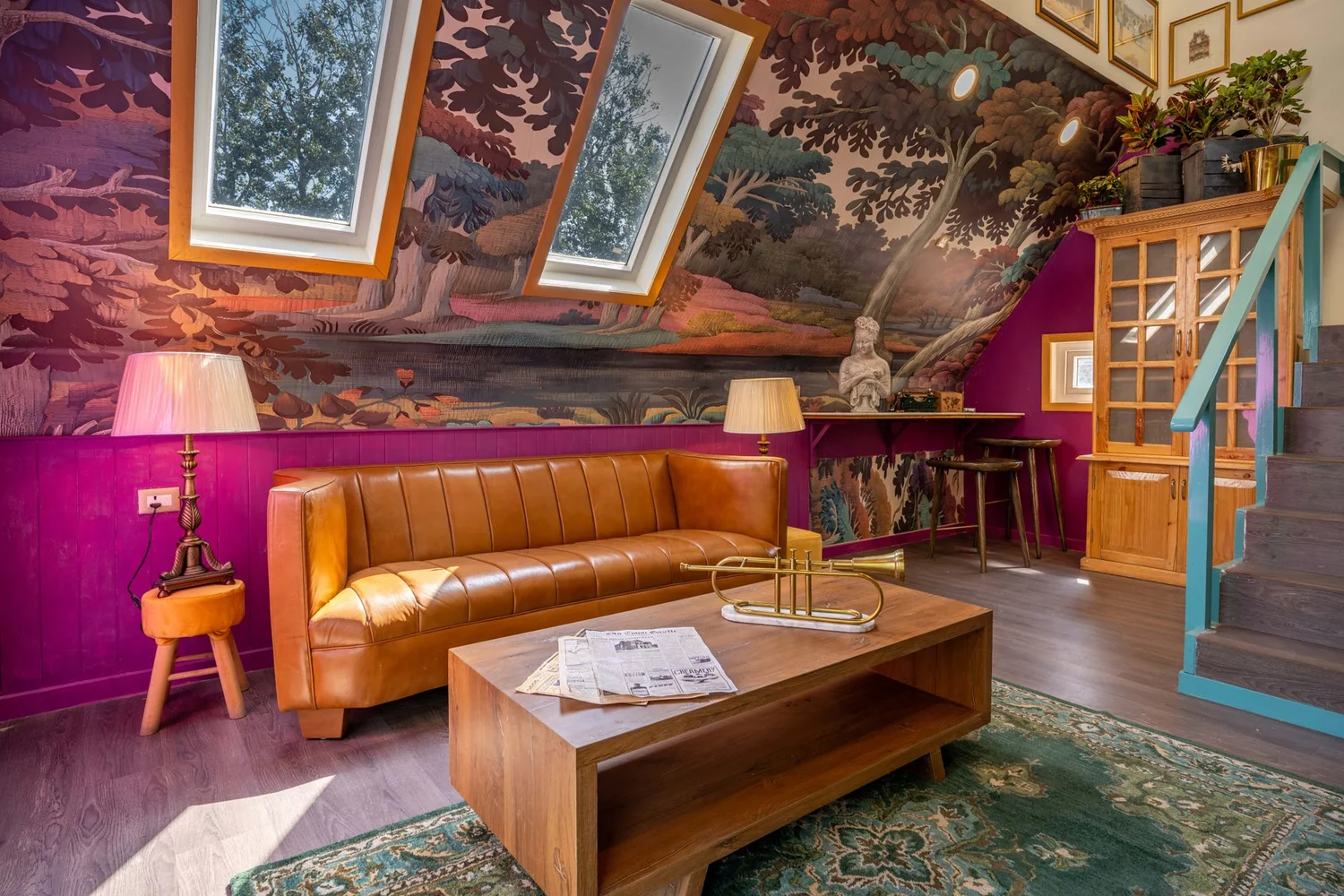 Salon dont le mur et le rampant sont couverts d'un décor peint de paysage boisé